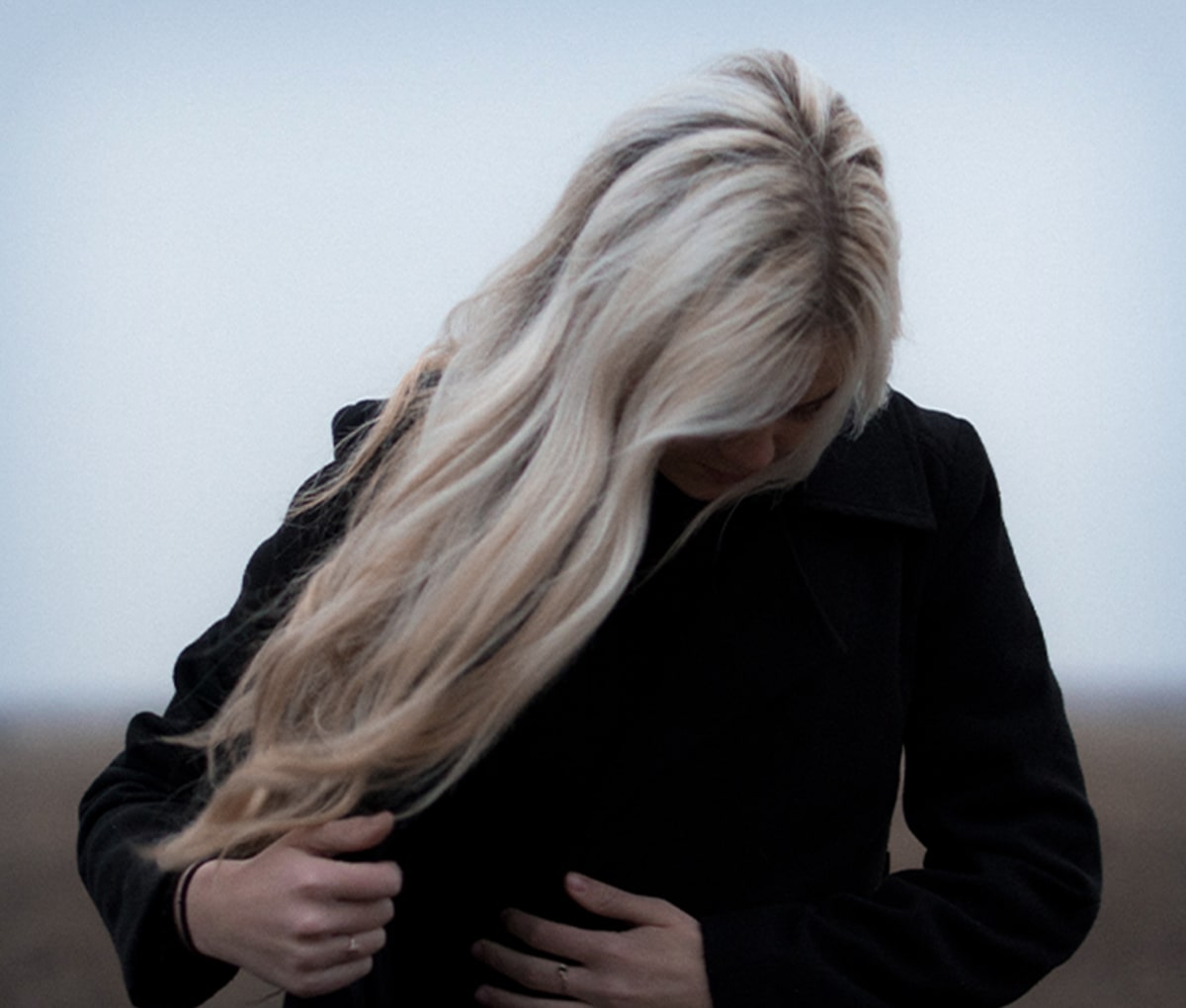 Frau mit langen Haaren in einem schwarzen Mantel